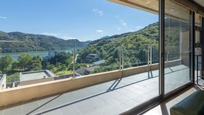 Un balcon avec vue sur un lac et des collines.