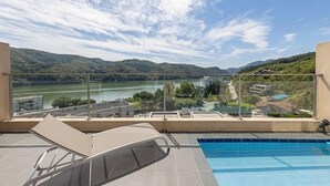 Une piscine sur le toit offrant une vue dégagée sur une rivière et des collines.