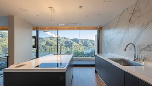 Une cuisine moderne dotée d’un grand îlot central, d’un évier intégré et offrant une vue sur un lac et des montagnes.