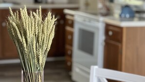 Een keuken met houten kastjes, een magnetron en een vaas met korelscheuten op een tafel.