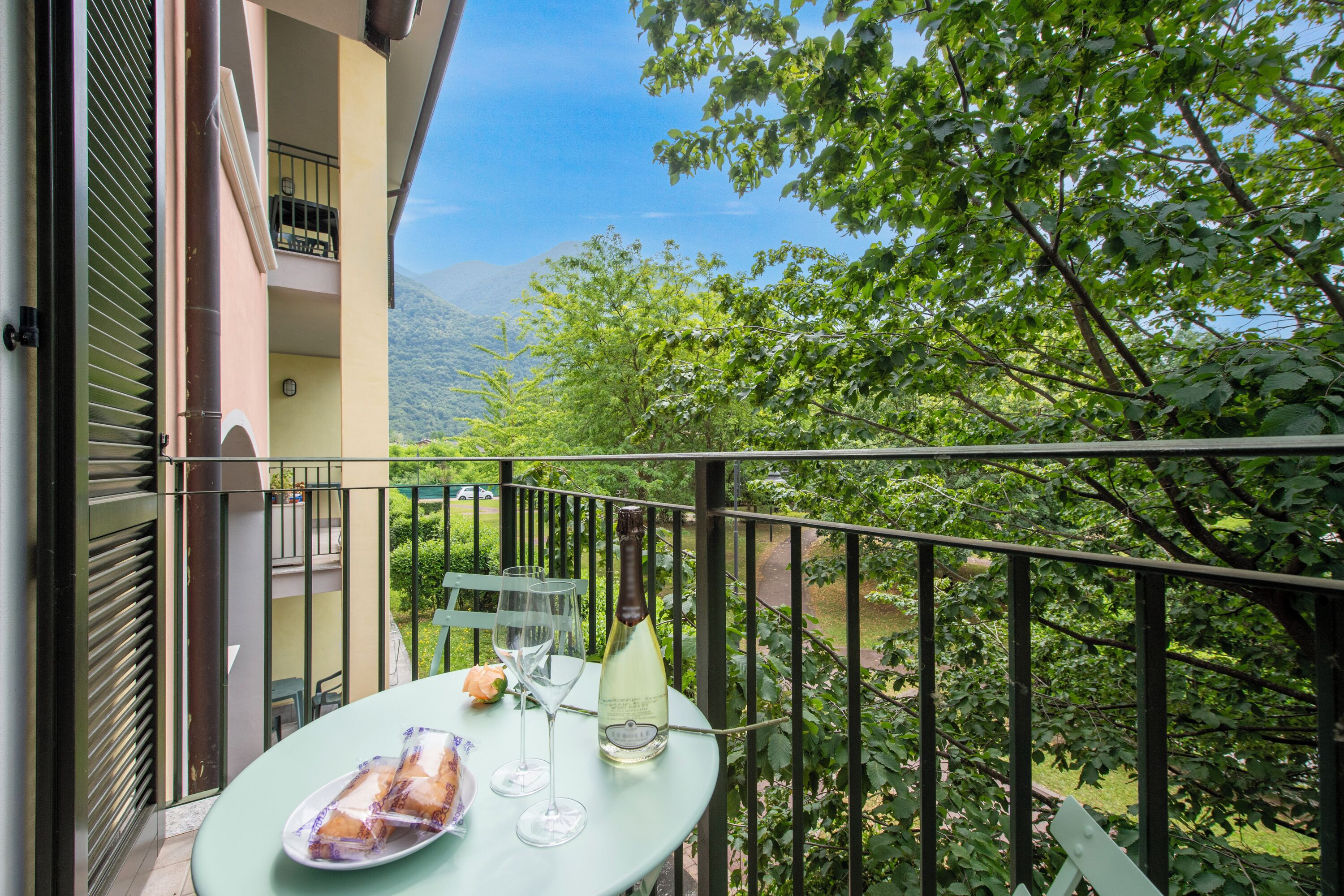 Un balcone con un tavolo apparecchiato per due persone, una bottiglia di vino e un piatto di cibo.