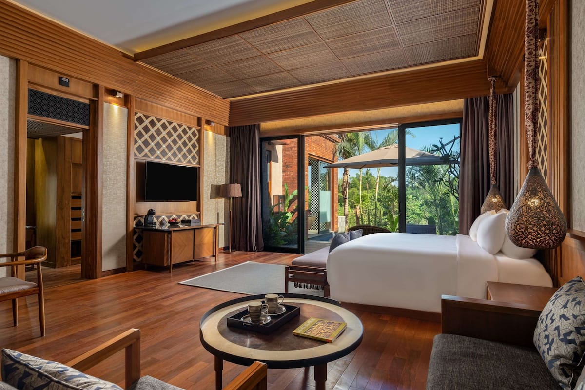 A spacious hotel room with a large bed, a sitting area with a coffee table, a desk, and a TV.