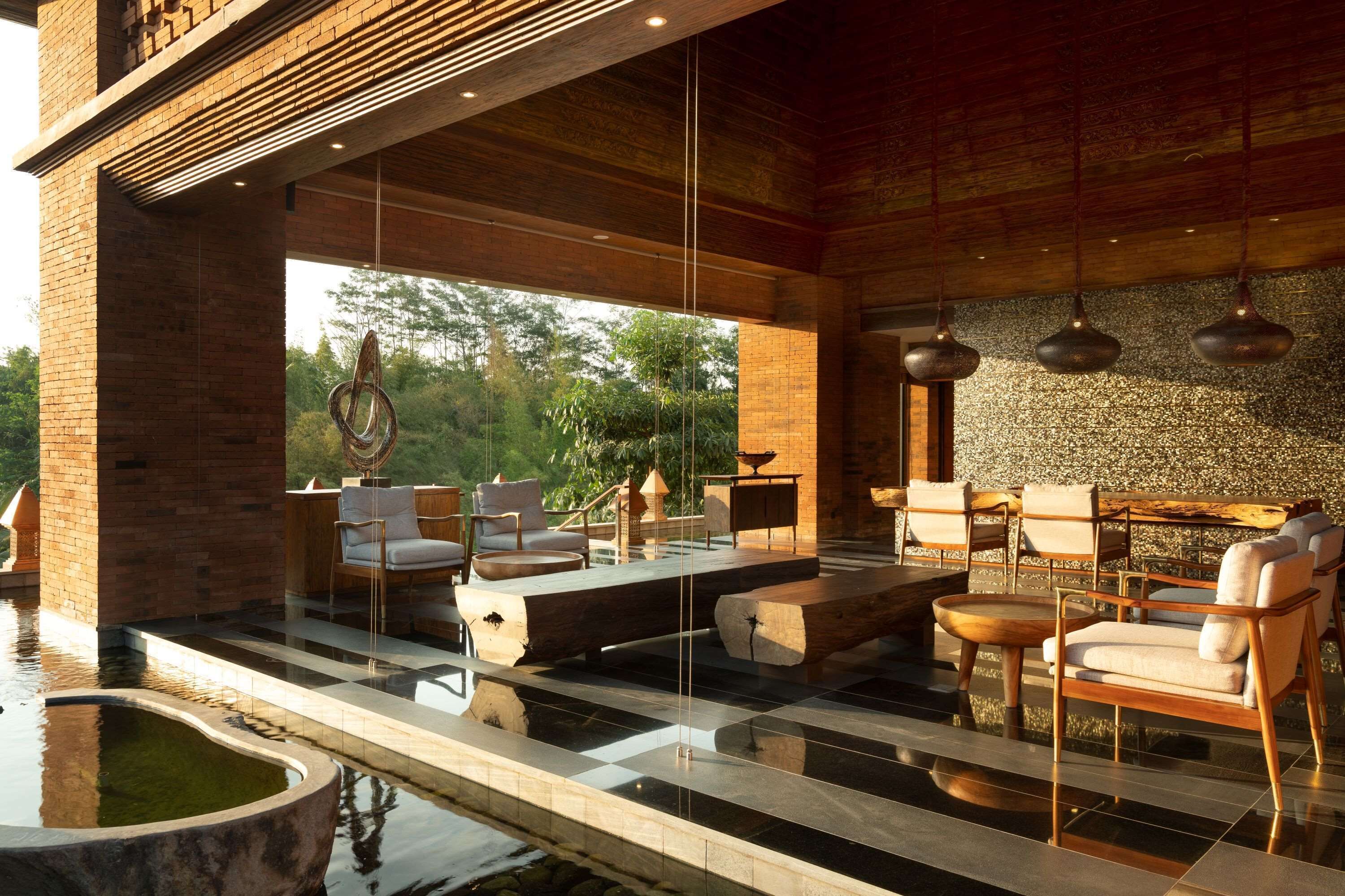 A modern outdoor lounge area with seating, a pool, and a view of the outdoors.