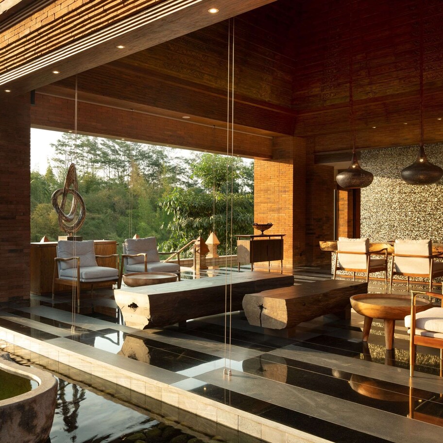 A modern outdoor lounge area with seating, a pool, and a view of the outdoors.