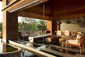 A modern outdoor lounge area with seating, a pool, and a view of the outdoors.