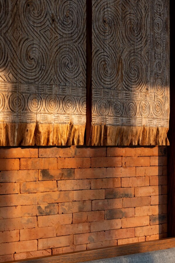 Una pared de ladrillo con un cortinero estampado.