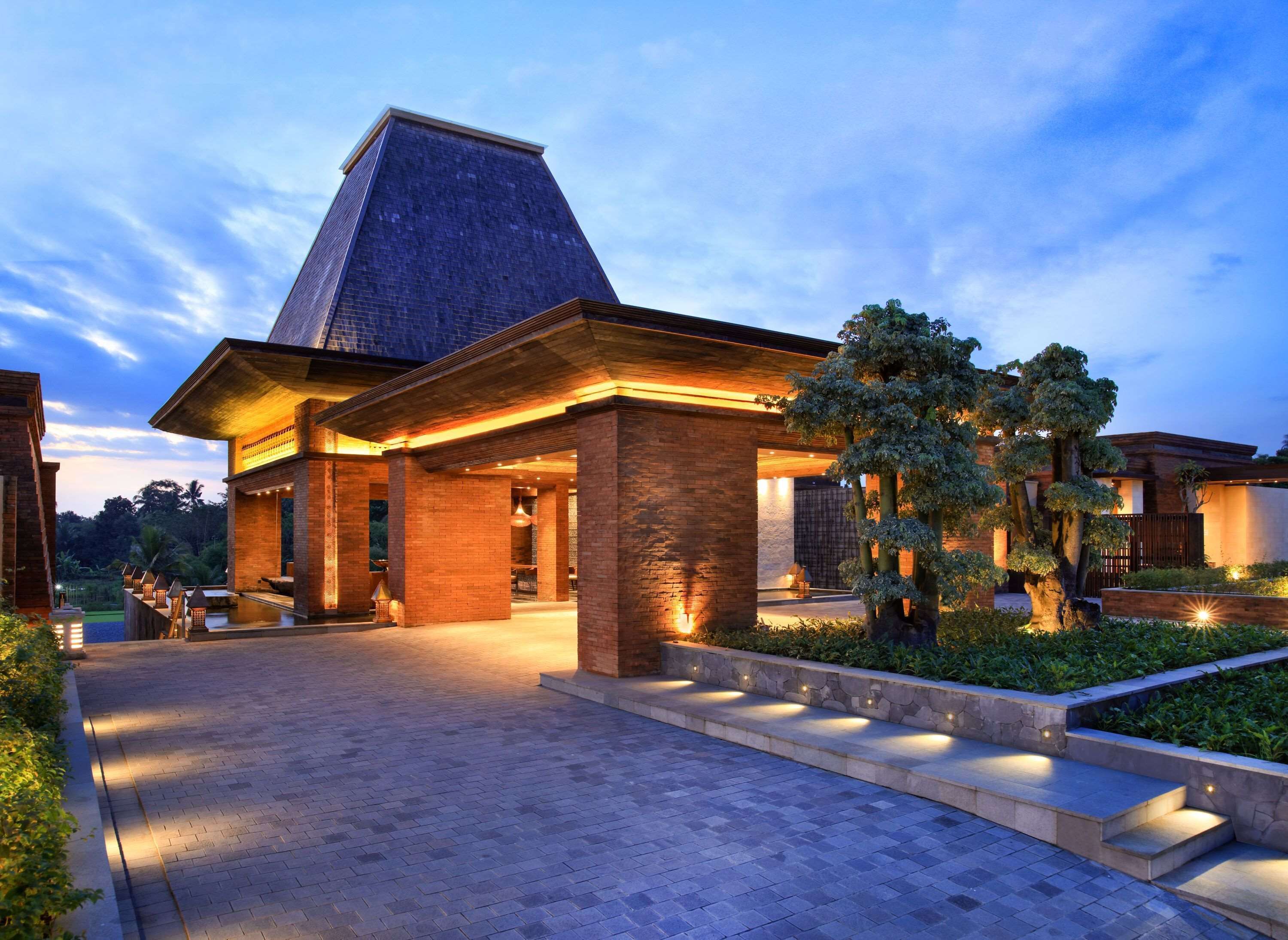 A modern building with a prominent triangular roof, a brick facade, and a well-lit entrance area with steps leading up to it.
