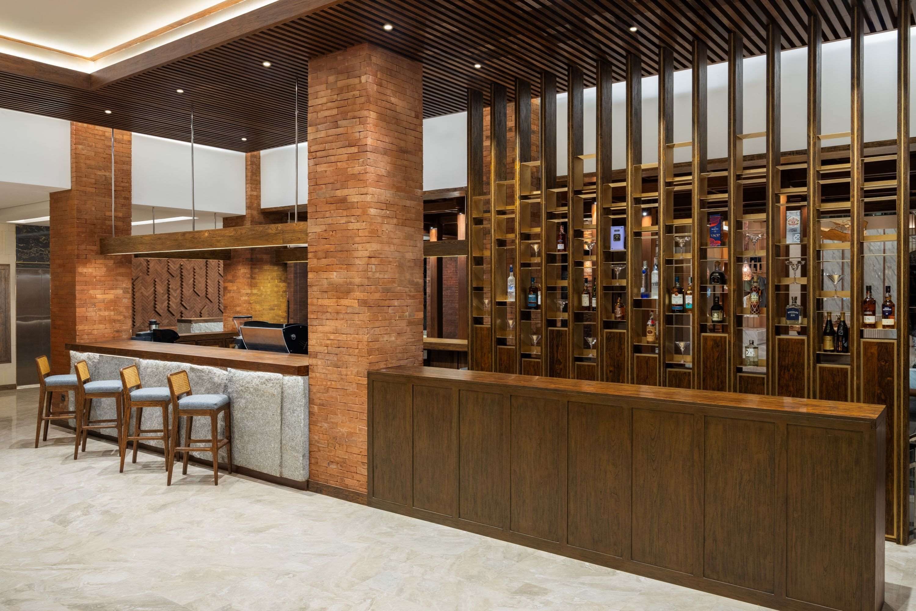 Zona de bar con una columna de ladrillo, mostrador de madera y taburetes.