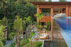 Une villa moderne dotée d’une piscine, d’un espace salon extérieur et d’une végétation tropicale luxuriante.