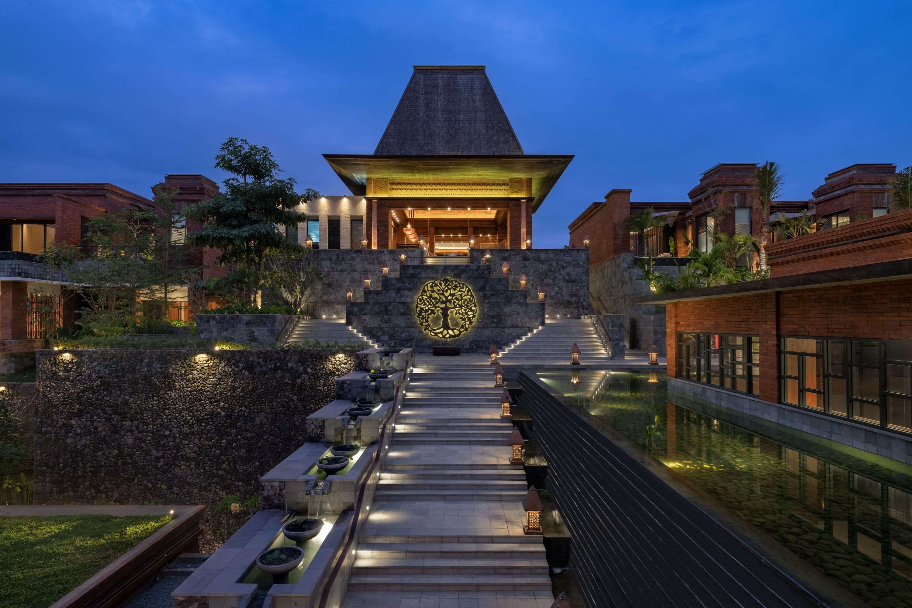A modern building with a central atrium, stone walls, and a water feature.