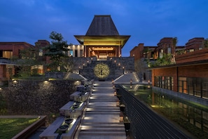A modern building with a central atrium, stone walls, and a water feature.