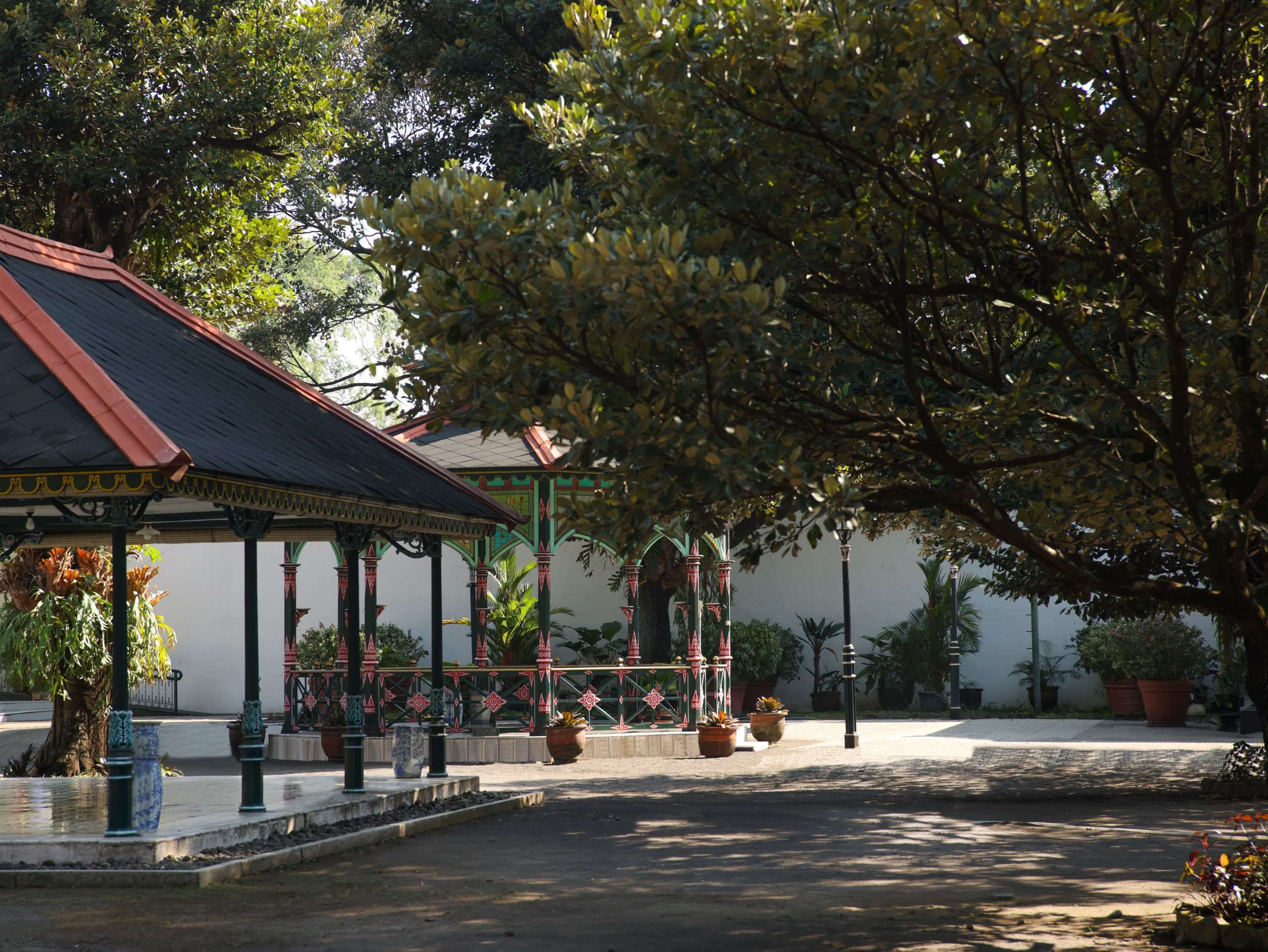 A traditional pavilion with a tiled roof, surrounded by potted plants and trees.