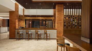 A modern bar area with a high counter, bar stools, and a wine display.