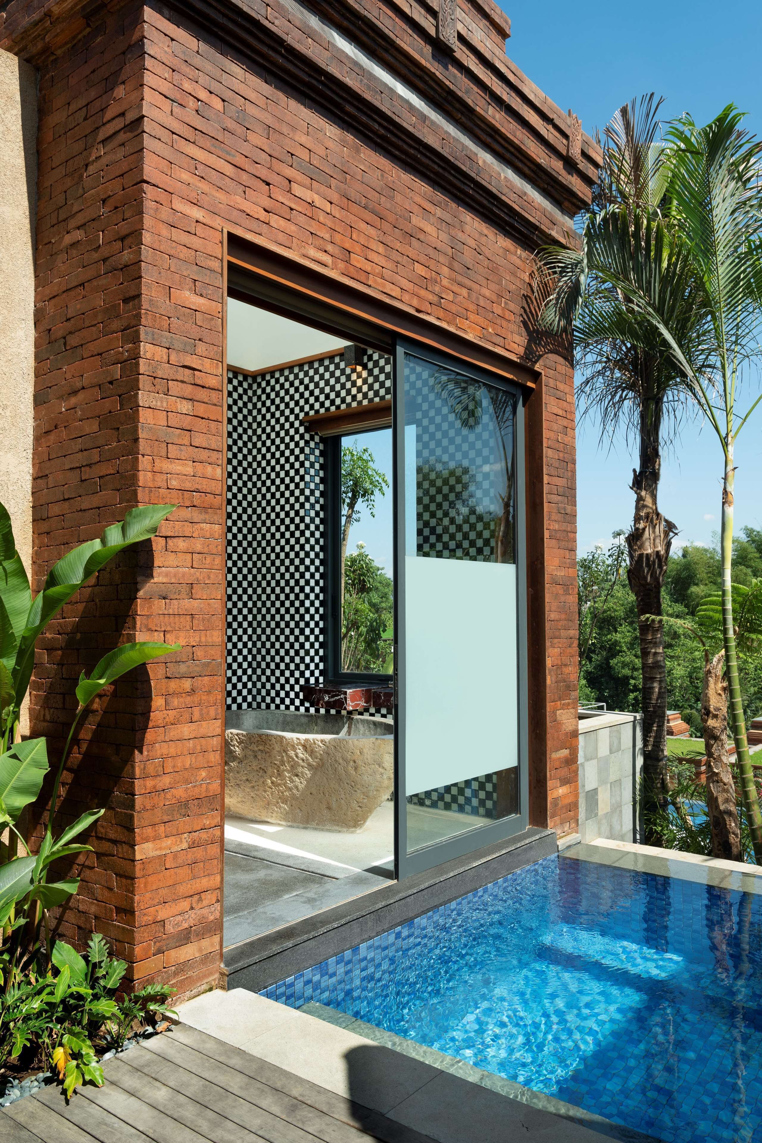 A modern building with a brick exterior, a glass door, and a pool area with a checkered tile pattern.