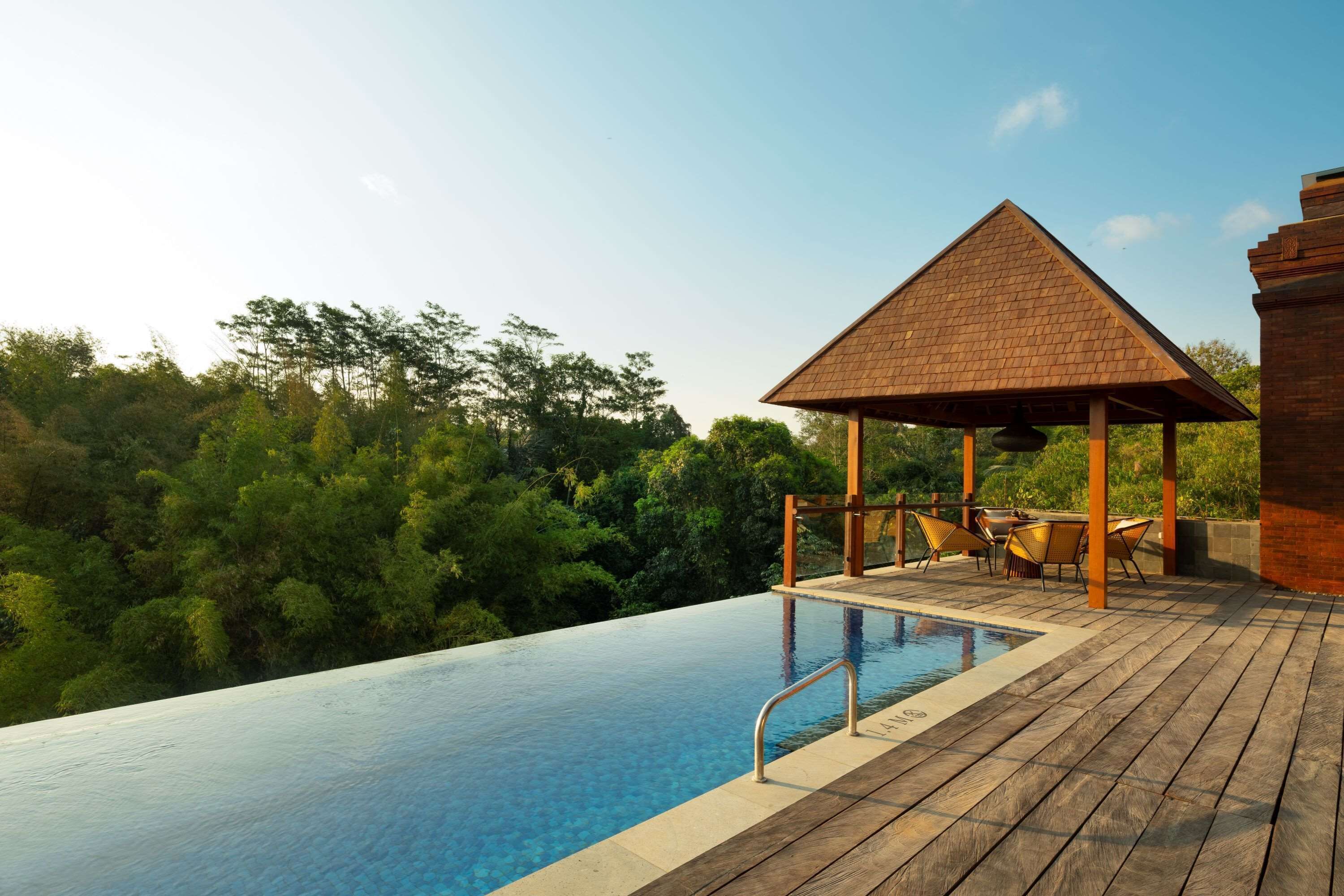 An infinity pool with a wooden deck and a gazebo.
