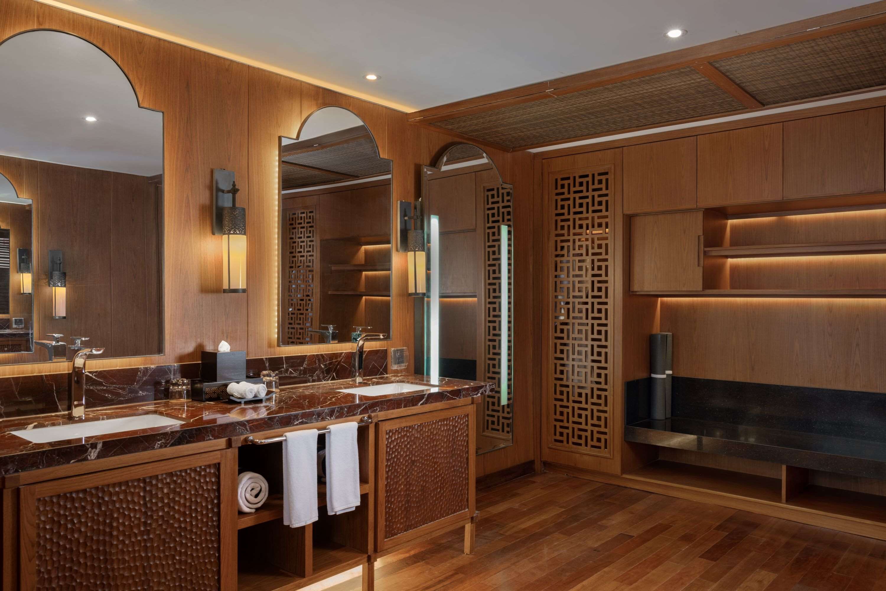 A modern bathroom with wooden paneling, a marble sink, and a large mirror.