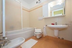 A bathroom with a bathtub, toilet, sink, and mirror.