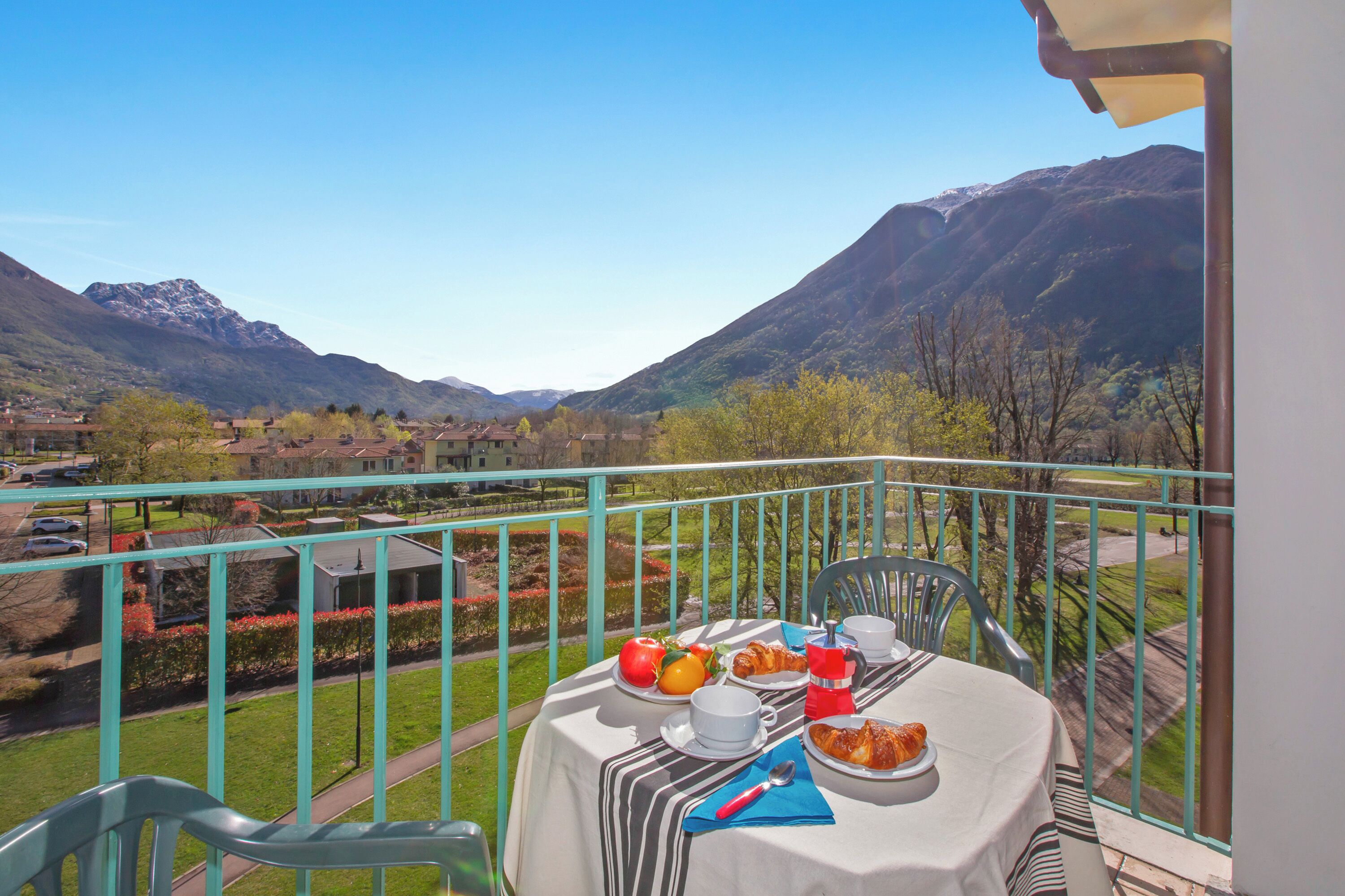 Un balcon avec une table préparée pour le petit-déjeuner, offrant une vue sur un paysage montagneux.