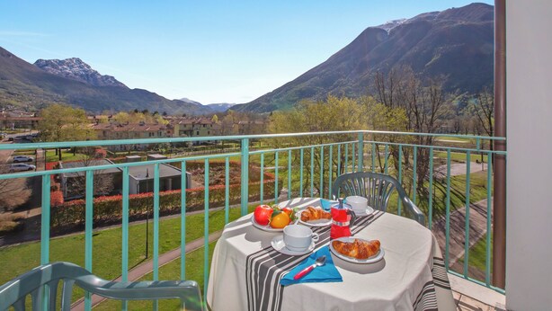 Ein Balkon mit Frühstückstisch, mit Blick auf eine gebirgige Landschaft.
