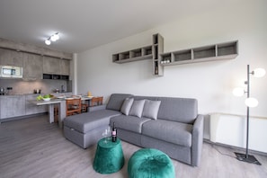 A modern living space with a grey sofa, a dining table, and a kitchen area. - Porto Letizia S16, Porlezza, Italy (Porlezza)