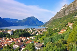 A mountainous town with a lake, surrounded by greenery and red-roofed buildings.