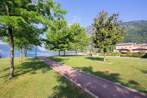A park with a paved walkway, trees, and a lake view. - Porto Letizia S16, Porlezza, Italy (Porlezza)