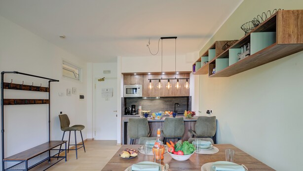 A modern kitchen with a built-in microwave, wooden shelves, and a dining area with a wooden table set for four. - Porto Letizia P5, Porlezza, Italy (Porlezza)