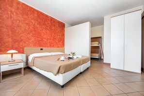 A hotel room with a bed, bedside table, lamp, and a wardrobe. - Porto Letizia S14 B1, Porlezza, Italy (Porlezza)
