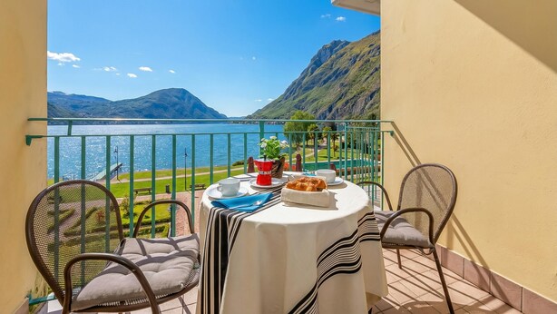 A balcony with a table set for two, overlooking a lake and mountains. - Porto Letizia S11 B1, Porlezza, Italy (Porlezza)