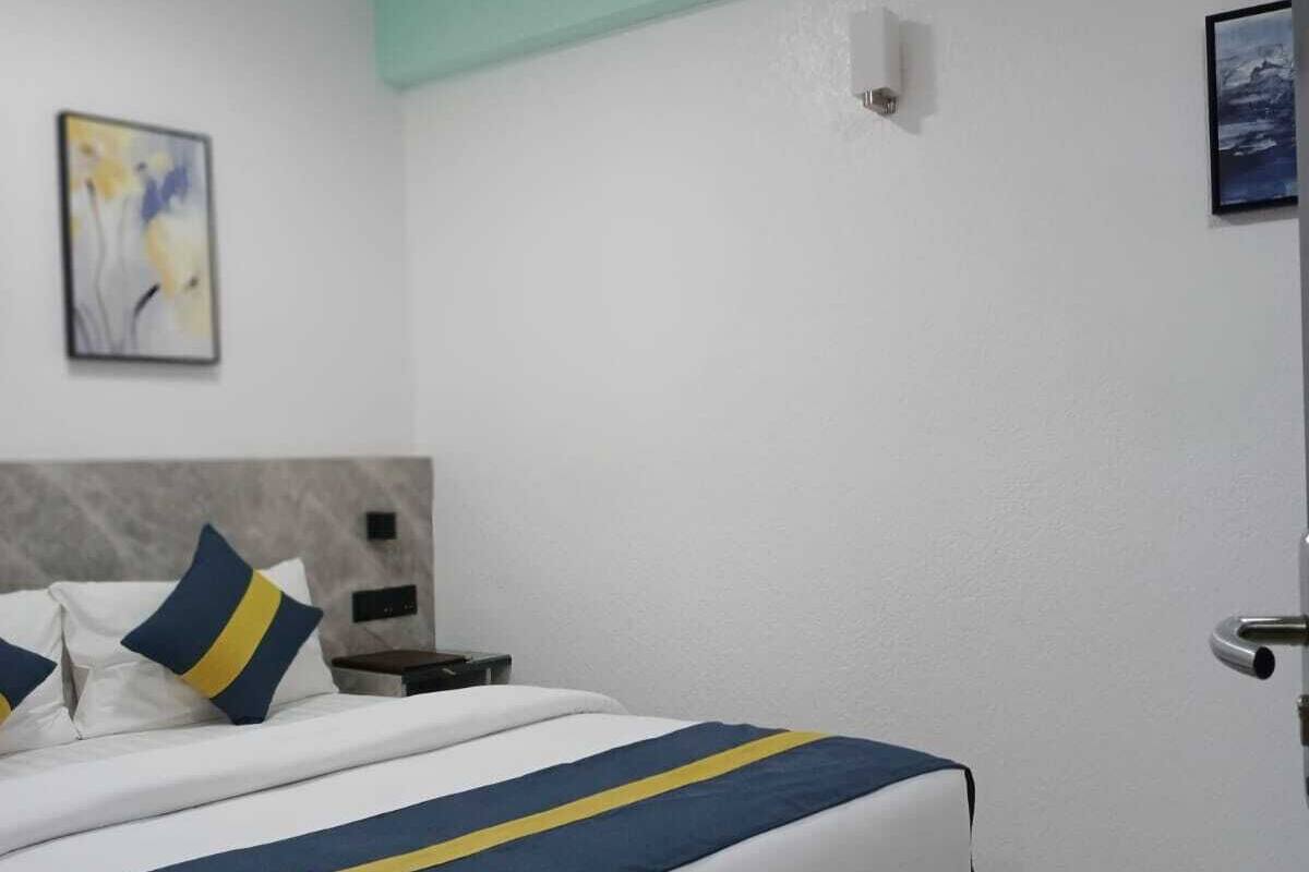 Ein Hotelzimmer mit Bett, Nachttisch, Wandleuchte und einem Gemälde.