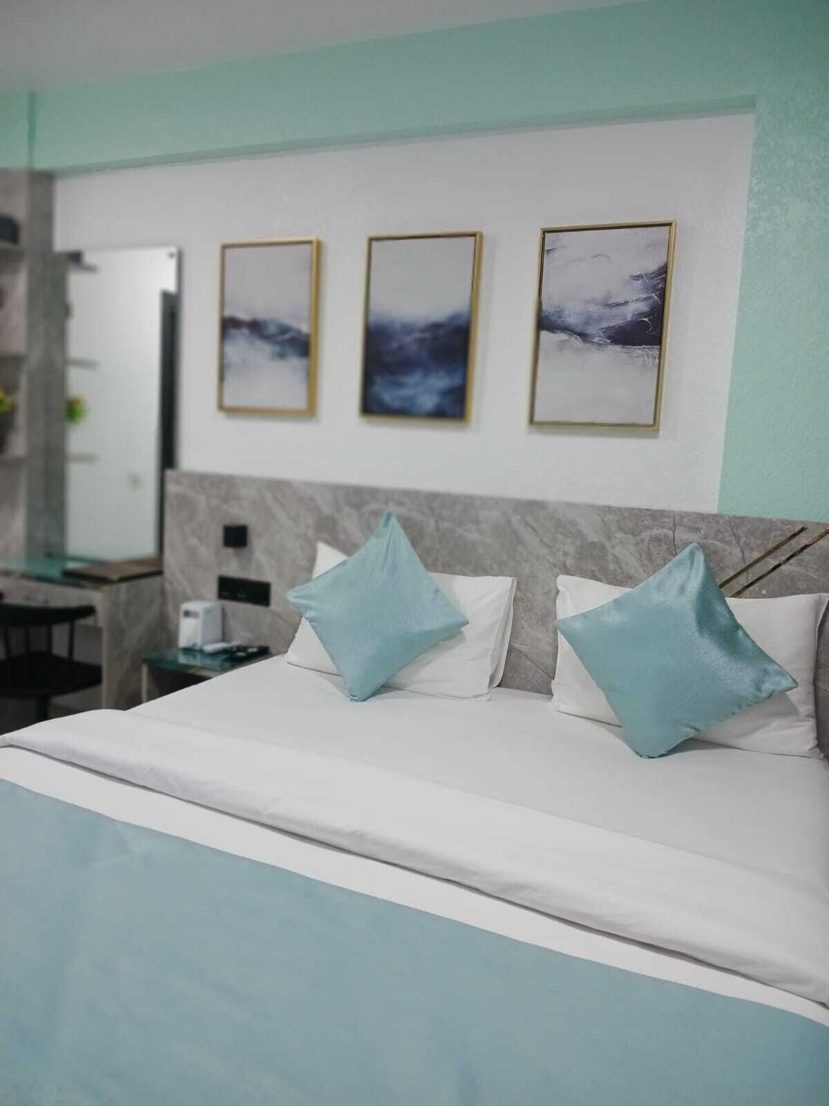 Una habitación de hotel con una cama, un escritorio y tres cuadros en la pared.