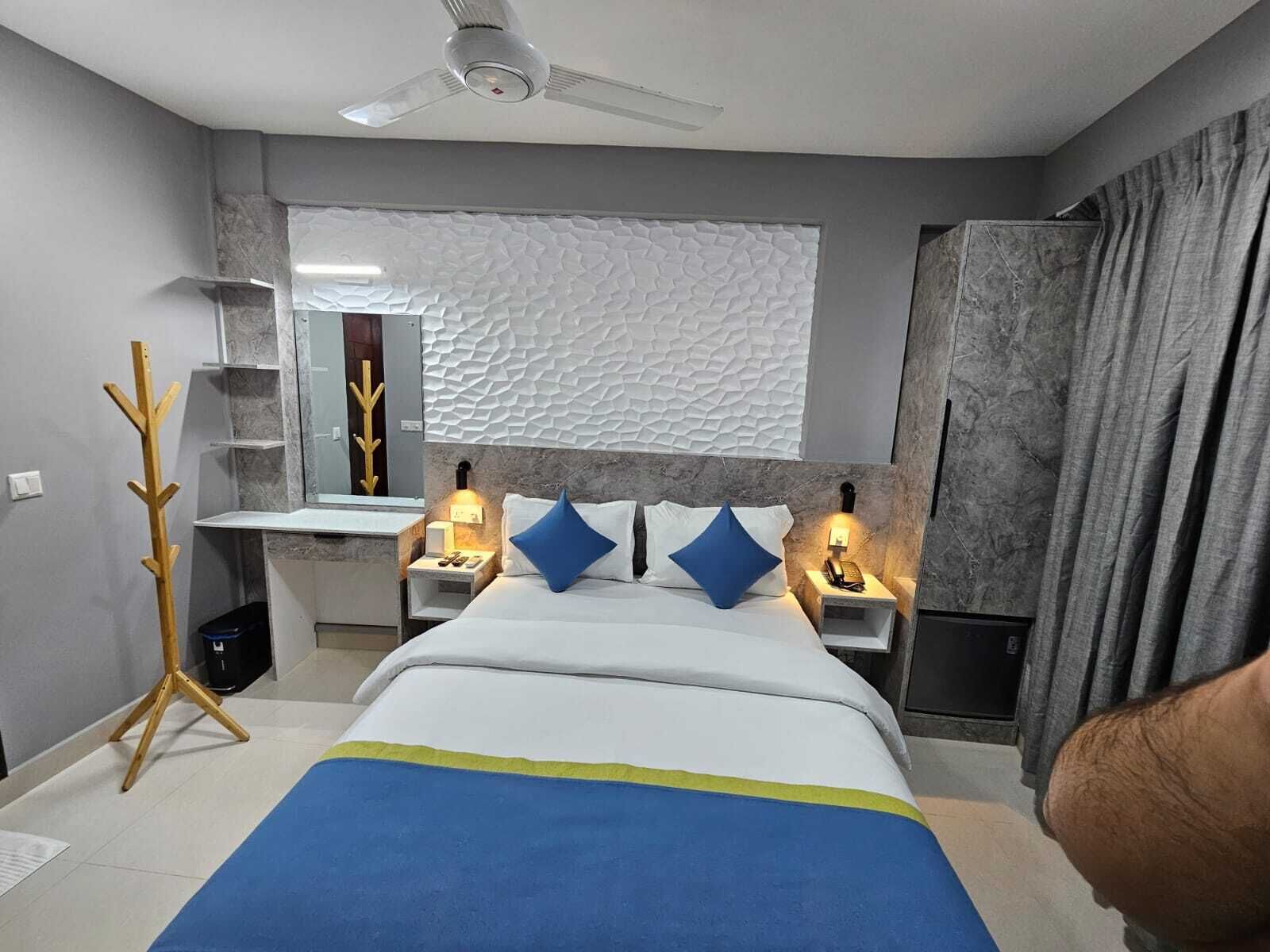 Un dormitorio moderno con una cama, mesitas de noche, un espejo y un ventilador de techo.