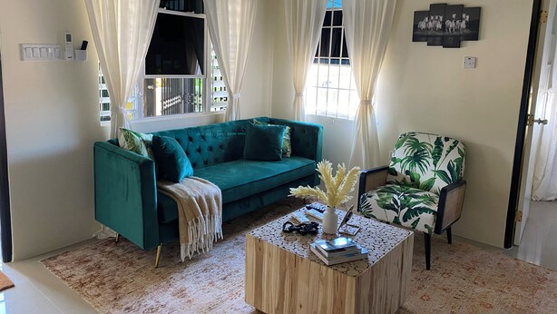 A living room with a teal sofa, a wooden coffee table, and a chair with a tropical print. - A taste of paradise, luxury villa on the beautiful Northern Coast! (Florence Hall Village)