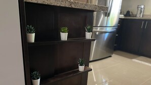 A kitchen with dark cabinetry, a stainless steel refrigerator, and three white potted plants on a shelf. - A taste of paradise, luxury villa on the beautiful Northern Coast! (Florence Hall Village)