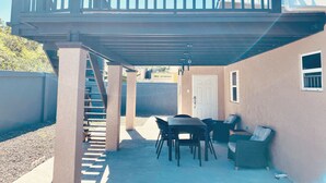 A covered patio area with a table and chairs, a balcony with railings, and a door leading to the interior. - A taste of paradise, luxury villa on the beautiful Northern Coast! (Florence Hall Village)