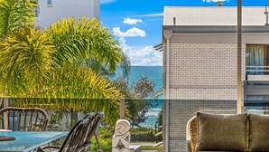 A patio with a table and chairs, a statue, and a view of the ocean.
