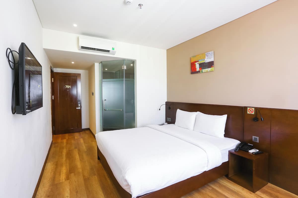 Ein Hotelzimmer mit Bett, Nachttisch und einem an der Wand befestigten Fernseher.