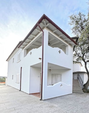 Un edificio a due piani con tetto piatto, pareti esterne bianche e una scala esterna che conduce al piano superiore.