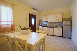 Cocina compacta con comedor, refrigerador, microondas y salpicadero de azulejos.