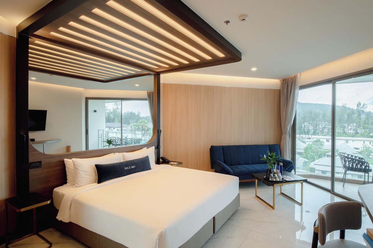 Une chambre d’hôtel moderne avec un grand lit, un canapé, une petite table et un téléviseur.