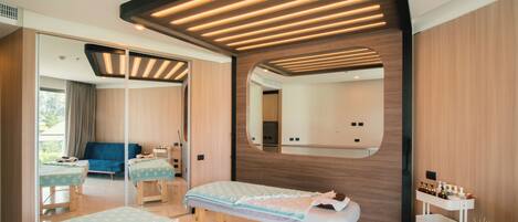 A modern bedroom with two beds, a large mirror, and a small table with amenities.