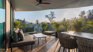 Un espace extérieur moderne aménagé avec une table et des chaises, un canapé et un ventilateur de plafond.