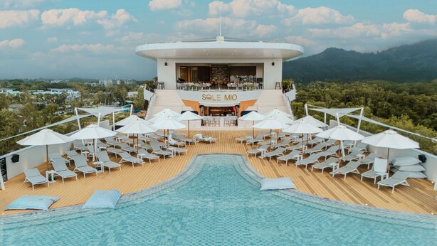 Un espace piscine avec des chaises longues et des parasols, un bar dont l’enseigne indique « SOLE MIO », et une vue sur le paysage environnant.
