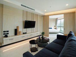 A modern living room with a large flat-screen TV mounted on the wall, a sofa, a coffee table, and a small side table.