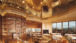 Eine moderne Bar mit einer gebogenen Theke, mehreren Flaschenregalen und einer Sitzecke mit Tischen und Stühlen.