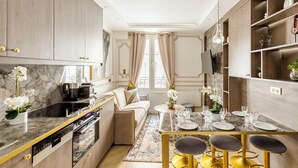 Una cocina moderna con encimeras de mármol, horno empotrado y zona de comedor con mesa de mármol y taburetes de bar.