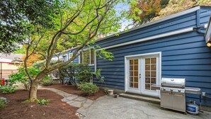A blue house with a patio, a grill, and a tree. - Perch - Wedgwood Haven: Spacious | Office | Family-Friendly (Seattle)