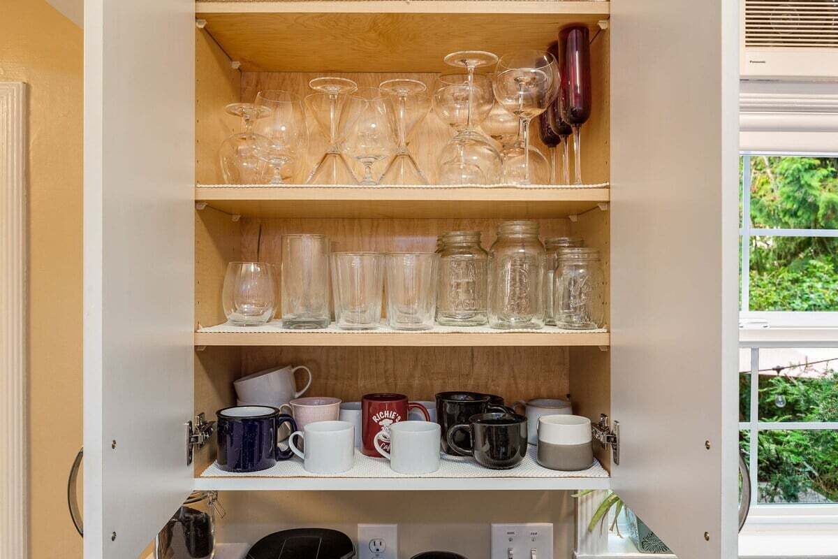 A cabinet with shelves holding various glassware and mugs.