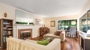 A living room with a fireplace, sofa, coffee table, and bookshelf. - Perch - Wedgwood Haven: Spacious | Office | Family-Friendly (Seattle)