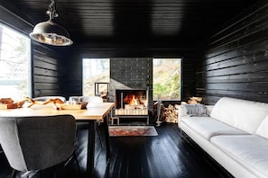 Cozy space with a fireplace, sofa, dining table, and large window.